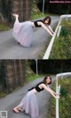 A woman in a black top and a pink tulle skirt leaning against a fence.