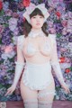 A woman in a white and pink lingerie posing in front of flowers.