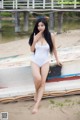 A woman in a white bathing suit posing on a boat.