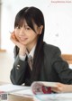 A young woman sitting at a desk with a book and pen.