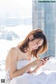 A woman sitting on a bed looking at her phone.