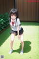 A girl in a school uniform is standing in the grass.