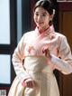 A woman in a pink and white hanbok is posing for a picture.