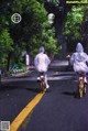 A couple of people riding bikes down a street in the rain.