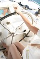 A woman is sitting at the helm of a boat.