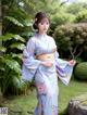 A woman in a blue kimono standing in a garden.