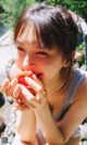 A young woman eating an apple in a park.