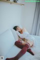 A woman laying on a bed in a white shirt and red stockings.