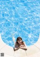 A woman laying on the edge of a swimming pool.